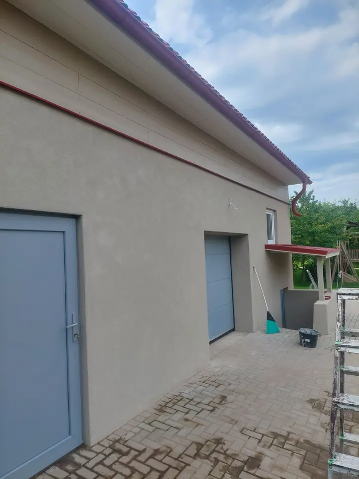 Apmesta mājas siena ar durvīm un garāžas vārtiem.