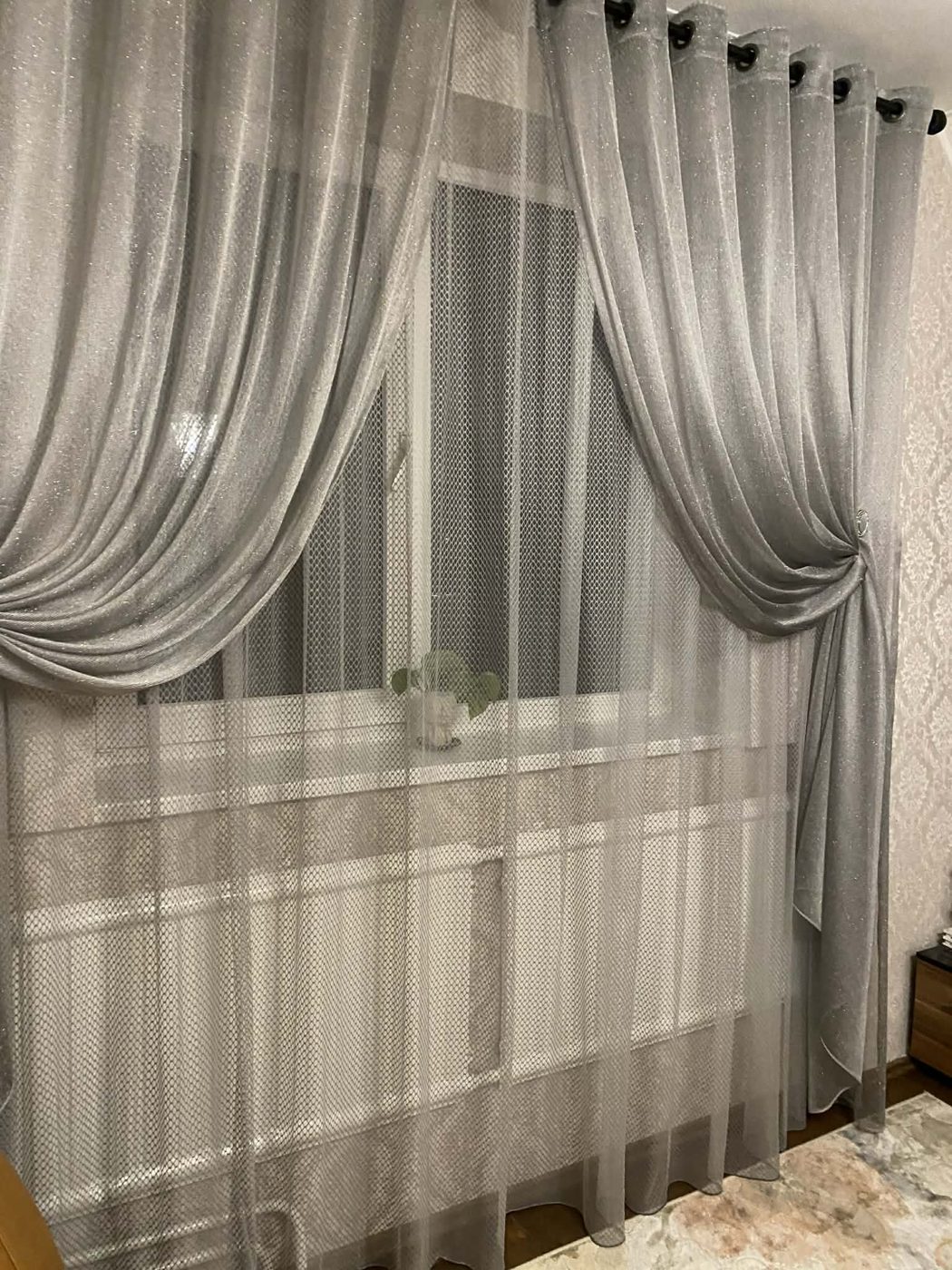 Tiulis ir pilka užuolaida prie lango