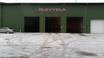 Plovyklos pastatas su atvirais įvažiavimo vartais ir asfaltuota aikštele