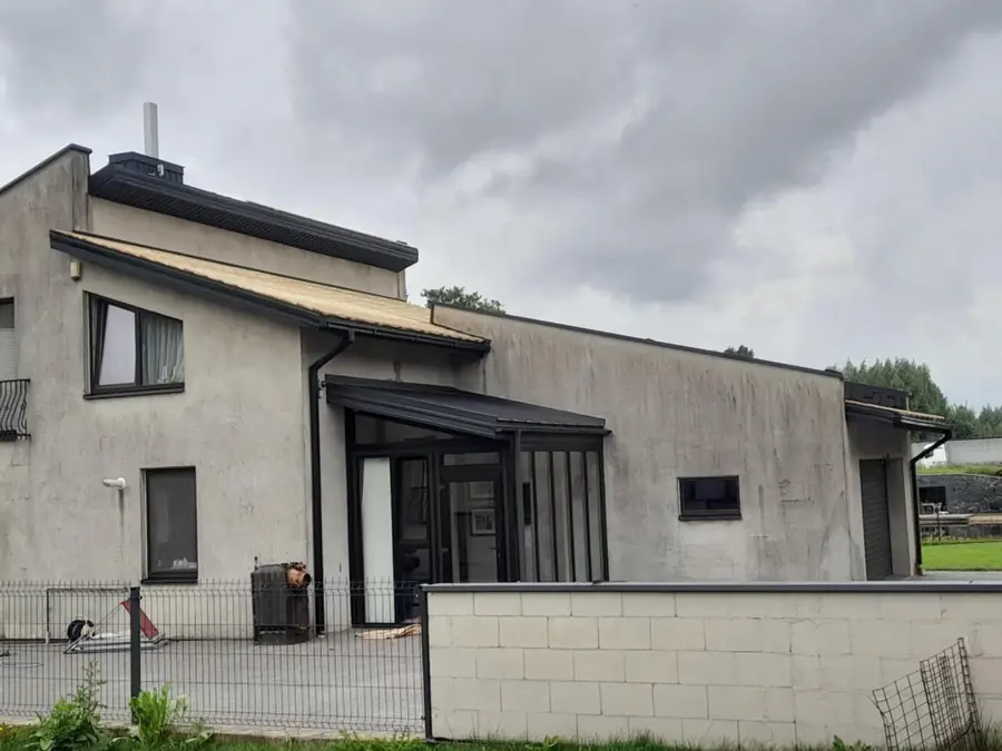 Šviesiai pilkas namo fasadas su stiklinėmis durimis