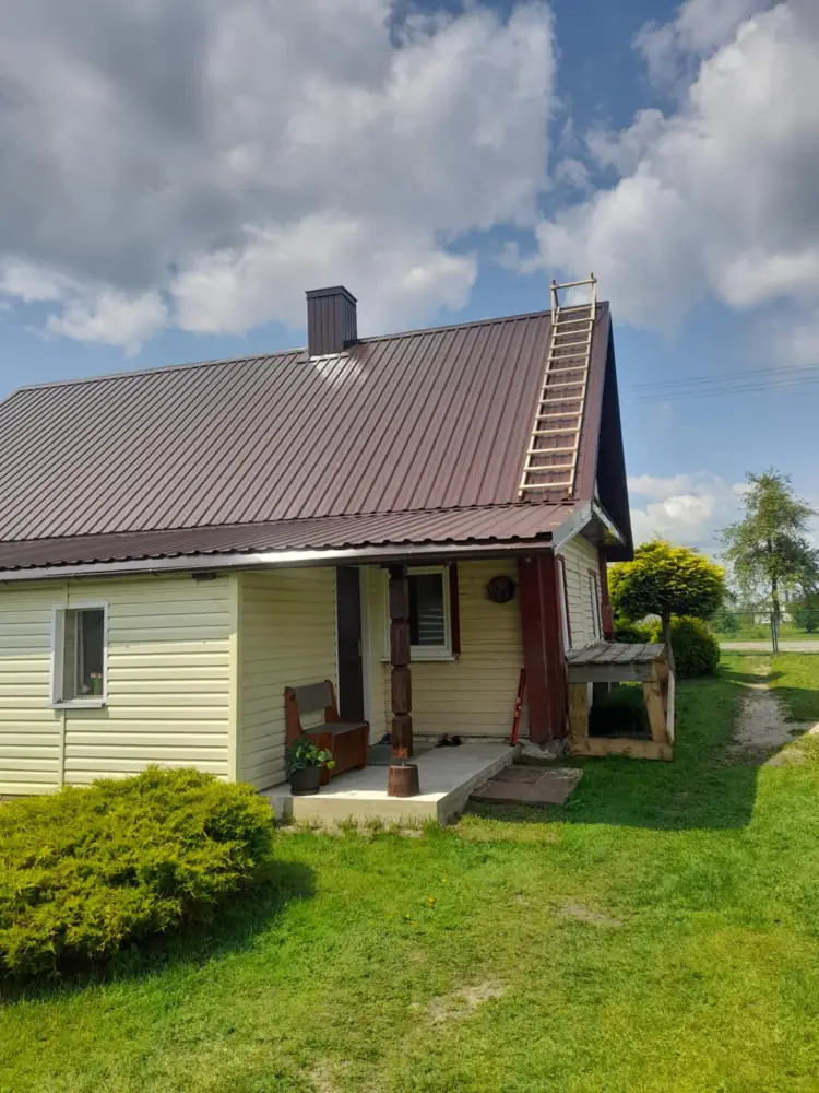 Nedidelis namas su nauju rudu stogu ir geltona apdaila