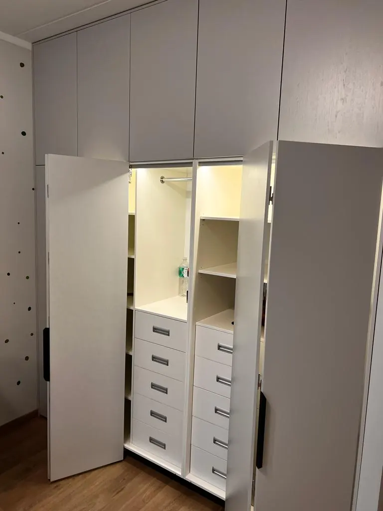 Atvērts skapis ar plauktiem un atvilktnēm iekšpusē