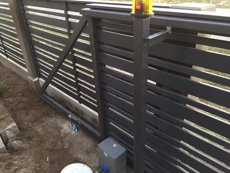 Tuvplānā tumši pelēku bīdāmo vārtu konsole, piedziņa un signāllampa uz staba